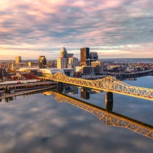 An aerial shot of the skyline of Louisville and the bridge at sunrise.